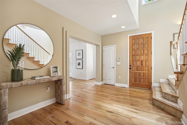 foyer featuring light wood-style floors, recessed lighting, baseboards, and stairs