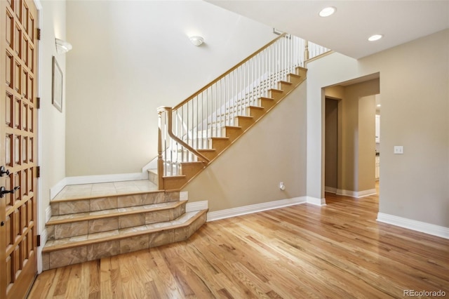 staircase with baseboards, wood finished floors, and recessed lighting