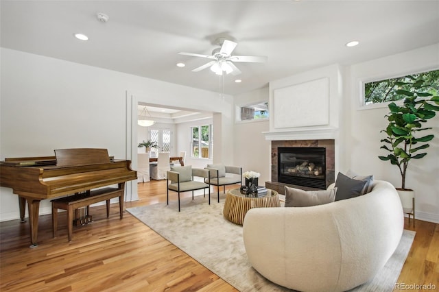 living area with recessed lighting, a fireplace, light wood-style flooring, and baseboards