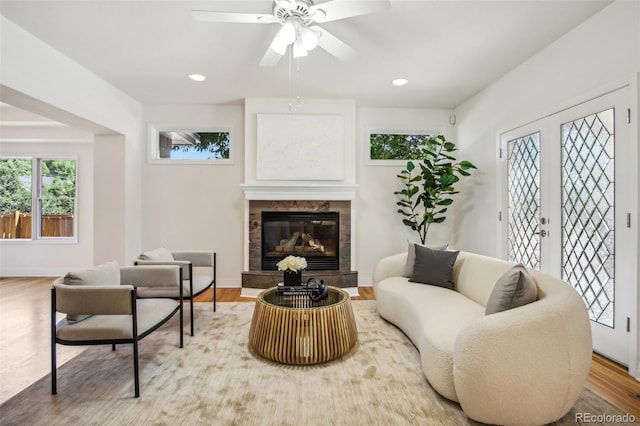 living room with baseboards, a tiled fireplace, wood finished floors, french doors, and recessed lighting