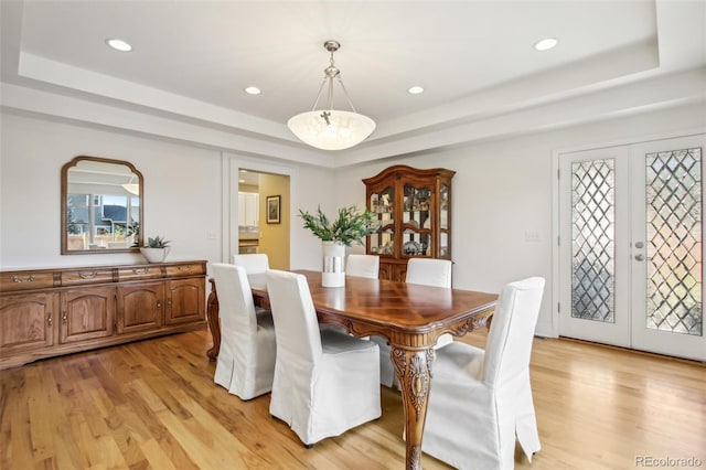 dining space featuring light wood-style floors, a tray ceiling, french doors, and recessed lighting