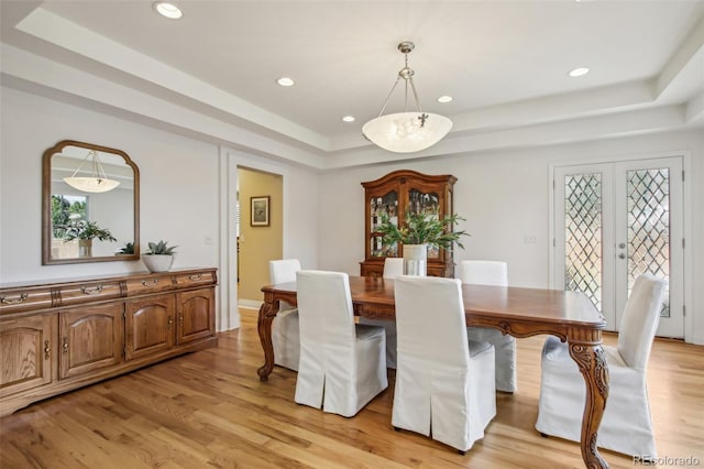 dining area featuring a tray ceiling, light wood-style flooring, and recessed lighting