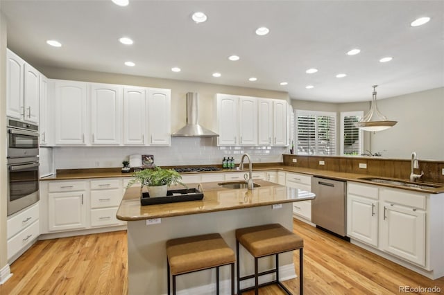 kitchen with wall chimney exhaust hood, a breakfast bar area, a sink, and stainless steel appliances