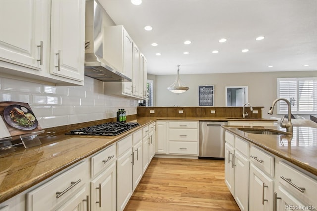 kitchen featuring wall chimney exhaust hood, stainless steel dishwasher, black gas stovetop, and white cabinets