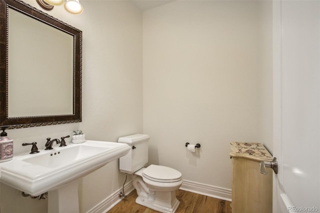 bathroom featuring baseboards, a sink, toilet, and wood finished floors