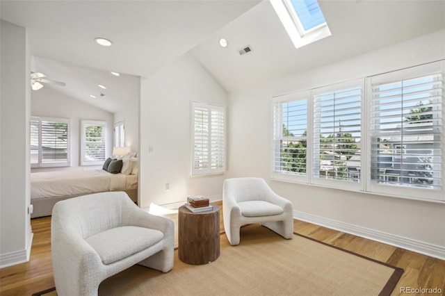 sitting room with vaulted ceiling with skylight, baseboards, visible vents, wood finished floors, and recessed lighting