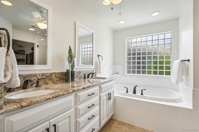 bathroom featuring a healthy amount of sunlight, a sink, a bath, and ceiling fan