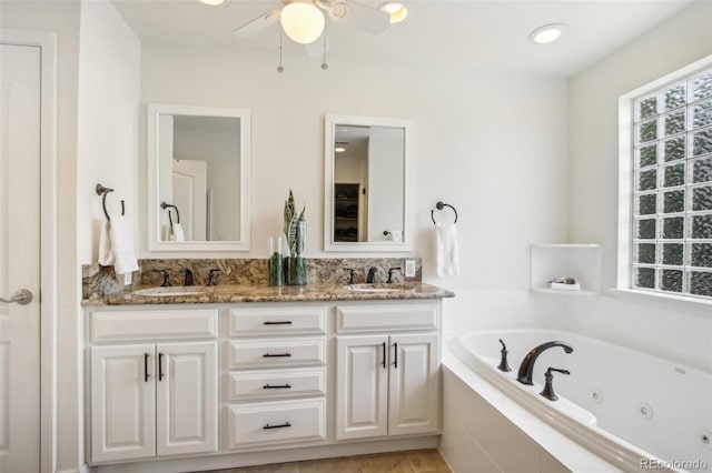 full bath featuring ceiling fan, a sink, a jetted tub, and double vanity