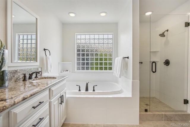 bathroom featuring a stall shower, vanity, and a bath