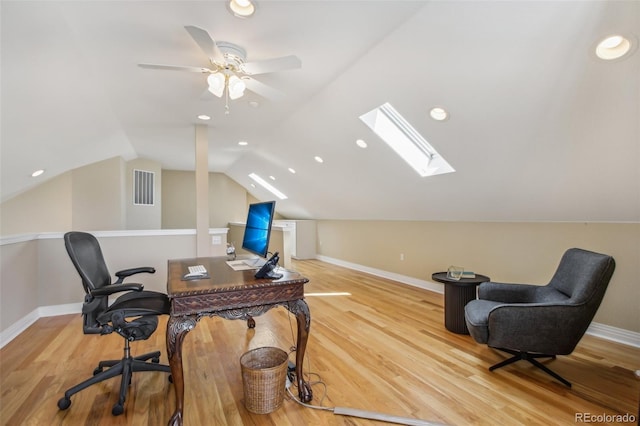 office area featuring lofted ceiling with skylight, visible vents, baseboards, and wood finished floors