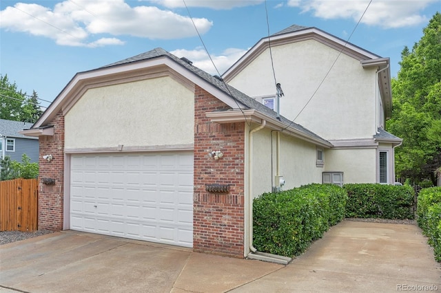 view of home's exterior featuring a garage, concrete driveway, brick siding, and stucco siding