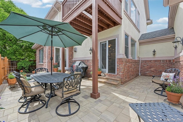 view of patio with entry steps, a grill, fence, and outdoor dining space