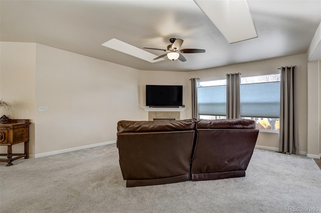 living room with ceiling fan, light colored carpet, and a skylight