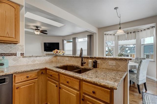 kitchen featuring light stone countertops, sink, pendant lighting, and dishwasher