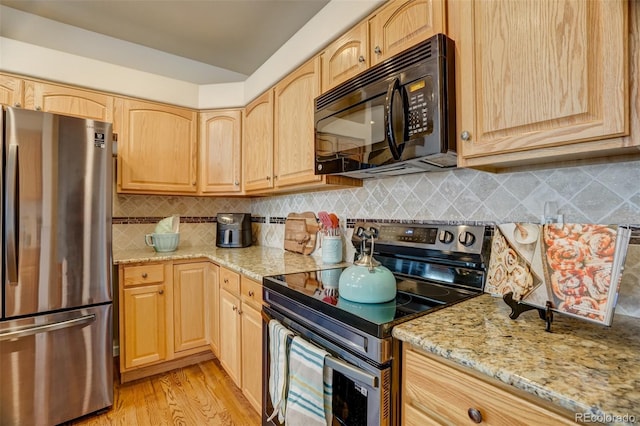 kitchen with light stone countertops, appliances with stainless steel finishes, decorative backsplash, and light brown cabinets