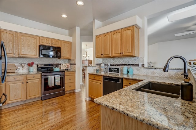 kitchen featuring black appliances, light stone counters, light hardwood / wood-style floors, and sink