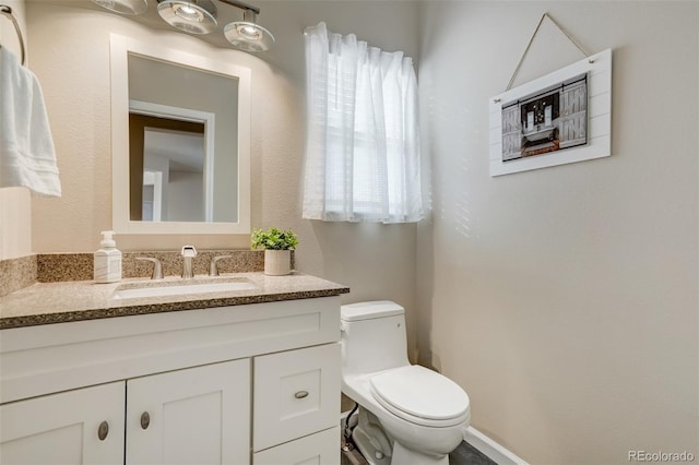 bathroom with vanity, toilet, and a healthy amount of sunlight