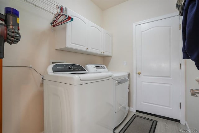 washroom featuring cabinets, light hardwood / wood-style floors, and washing machine and clothes dryer