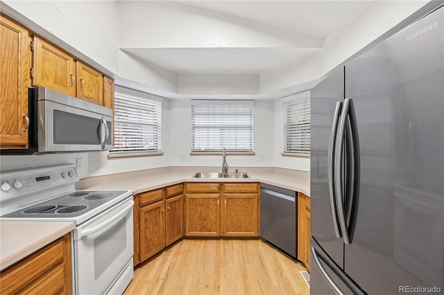 7888 S Poplar Way, Centennial, CO 80112 - kitchen featuring stainless steel appliances, light wood finished floors, light countertops, a tray ceiling, and brown cabinets