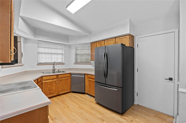 7888 S Poplar Way, Centennial, CO 80112 - kitchen with stainless steel appliances, vaulted ceiling, light wood-style floors, light countertops, and brown cabinets