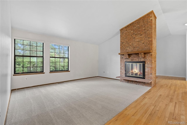 7888 S Poplar Way, Centennial, CO 80112 - unfurnished living room with vaulted ceiling, a brick fireplace, and wood finished floors