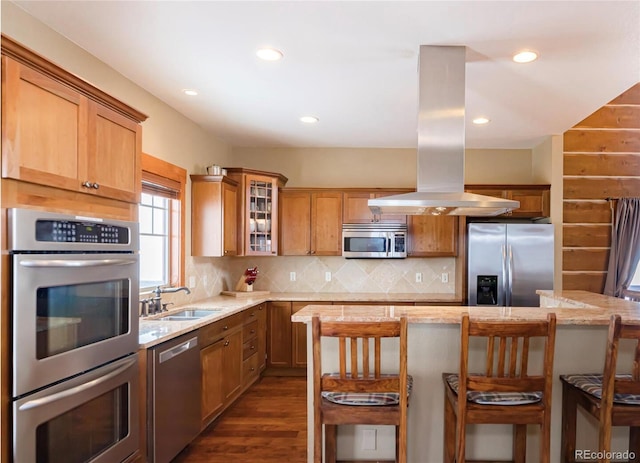 kitchen featuring backsplash, a kitchen breakfast bar, sink, appliances with stainless steel finishes, and island exhaust hood