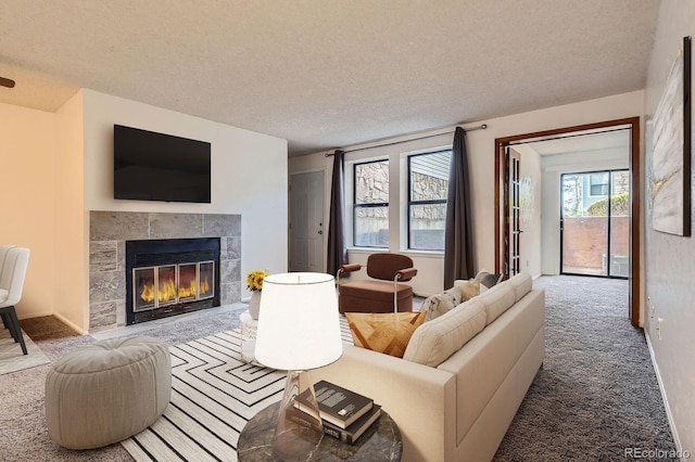 carpeted living room with baseboards, a textured ceiling, and a tiled fireplace