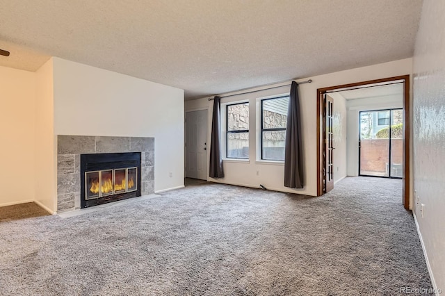 unfurnished living room with baseboards, a fireplace, a textured ceiling, and carpet