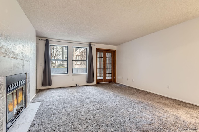 unfurnished living room featuring a textured ceiling, baseboards, carpet, and a tile fireplace