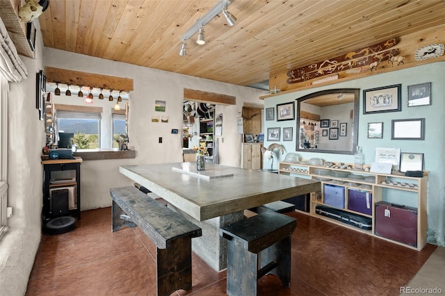 dining space with rail lighting and wooden ceiling