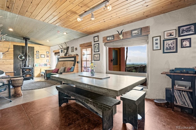 dining area featuring wooden ceiling, a wood stove, track lighting, and vaulted ceiling