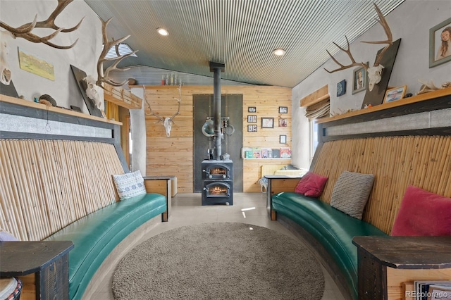 sitting room featuring lofted ceiling, a wood stove, and wood walls