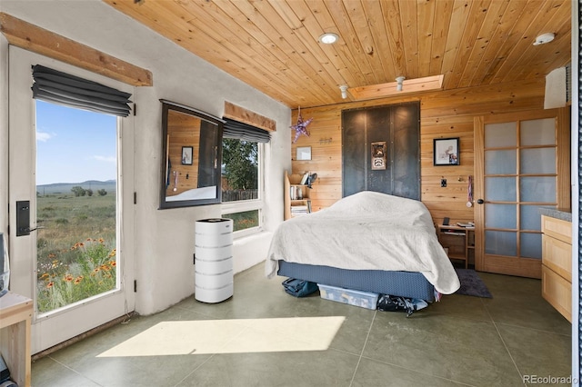 bedroom featuring wooden ceiling, wooden walls, and multiple windows