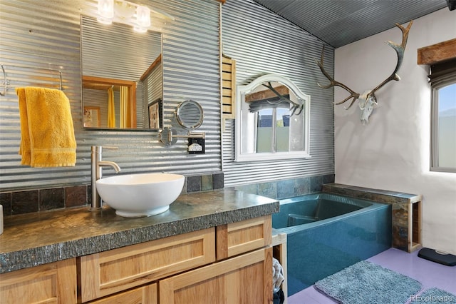 bathroom with a wealth of natural light, a tub, backsplash, and vanity