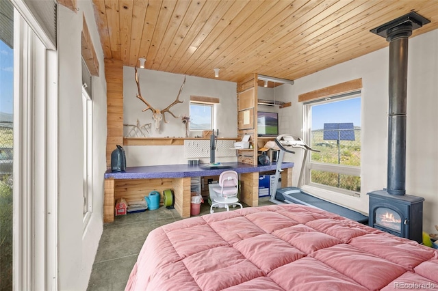 bedroom with wooden ceiling, a wood stove, and concrete flooring