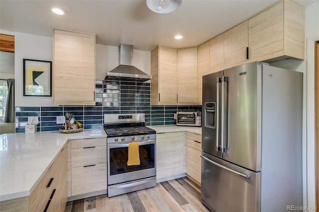 3010 Zinnia Ct, Golden, CO 80401 - kitchen featuring stainless steel appliances, wall chimney exhaust hood, light brown cabinets, a peninsula, and recessed lighting