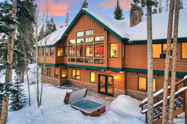 snow covered property featuring an outdoor hot tub