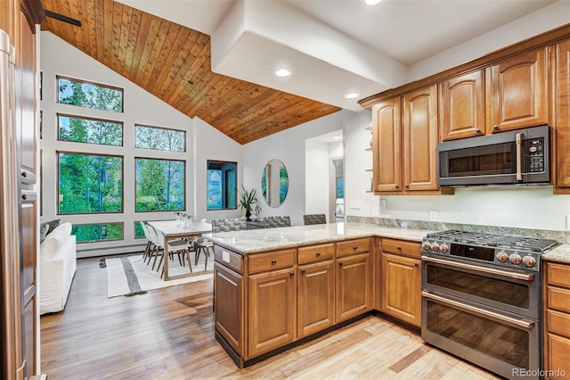 kitchen with light stone countertops, kitchen peninsula, appliances with stainless steel finishes, and light hardwood / wood-style flooring