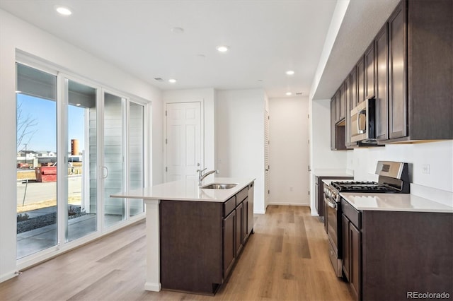 kitchen featuring sink, light hardwood / wood-style floors, an island with sink, and appliances with stainless steel finishes