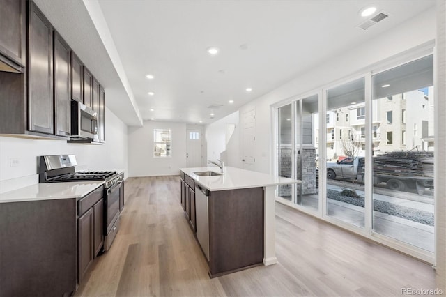 kitchen with sink, dark brown cabinets, light hardwood / wood-style floors, and appliances with stainless steel finishes