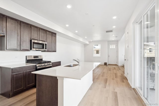 kitchen featuring appliances with stainless steel finishes, sink, a center island with sink, and dark brown cabinetry