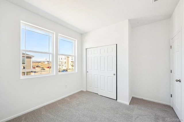 unfurnished bedroom featuring light colored carpet and a closet