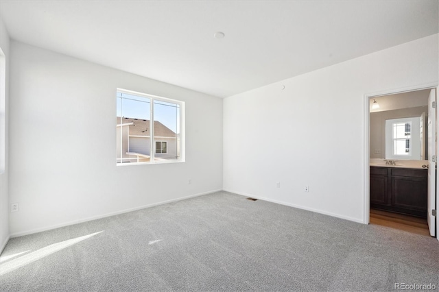 carpeted spare room featuring sink and a wealth of natural light