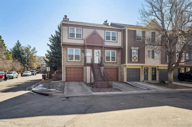 multi unit property featuring driveway, a chimney, a garage, and stairway