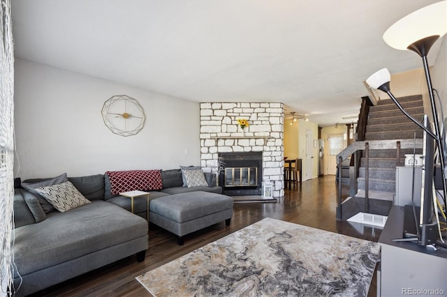 living area with a fireplace, stairway, and dark wood-type flooring