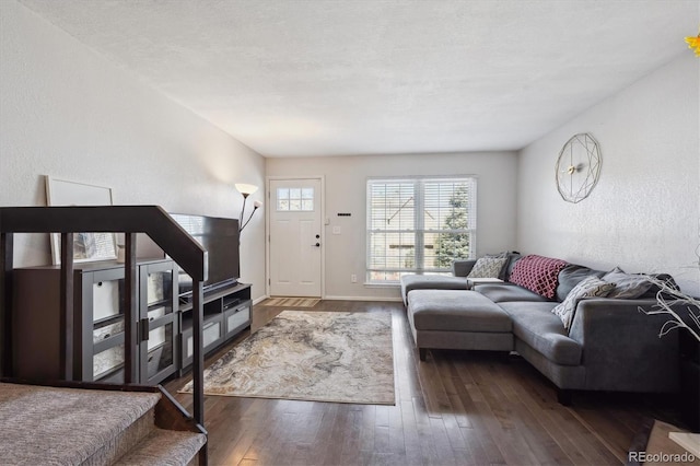 living area with a textured ceiling, a textured wall, wood-type flooring, and baseboards