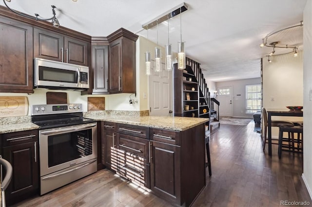 kitchen with light stone counters, appliances with stainless steel finishes, dark wood-type flooring, and dark brown cabinets