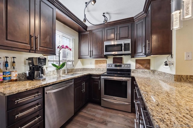 kitchen with dark wood-style floors, appliances with stainless steel finishes, light stone countertops, dark brown cabinets, and a sink