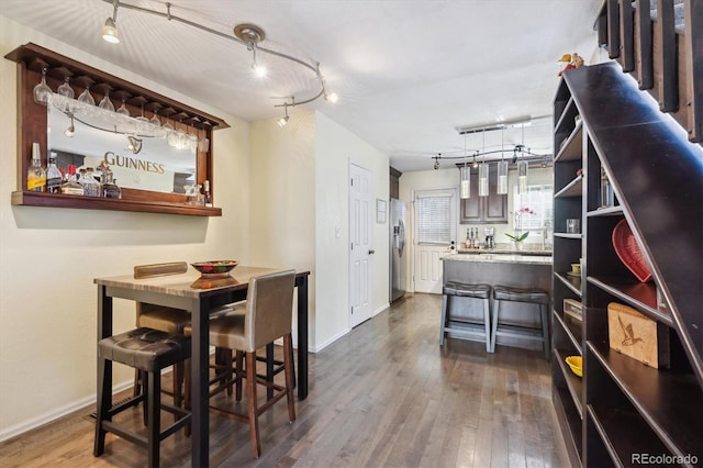 dining room with baseboards, dark wood finished floors, and track lighting