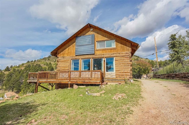 rear view of property featuring a wooden deck and a yard